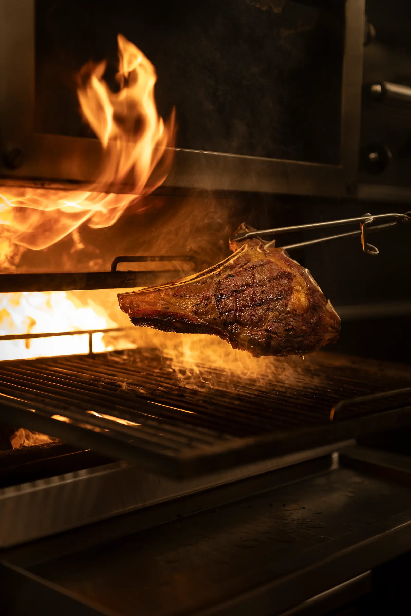 Beef on the bone above the flames of the charcoal grill