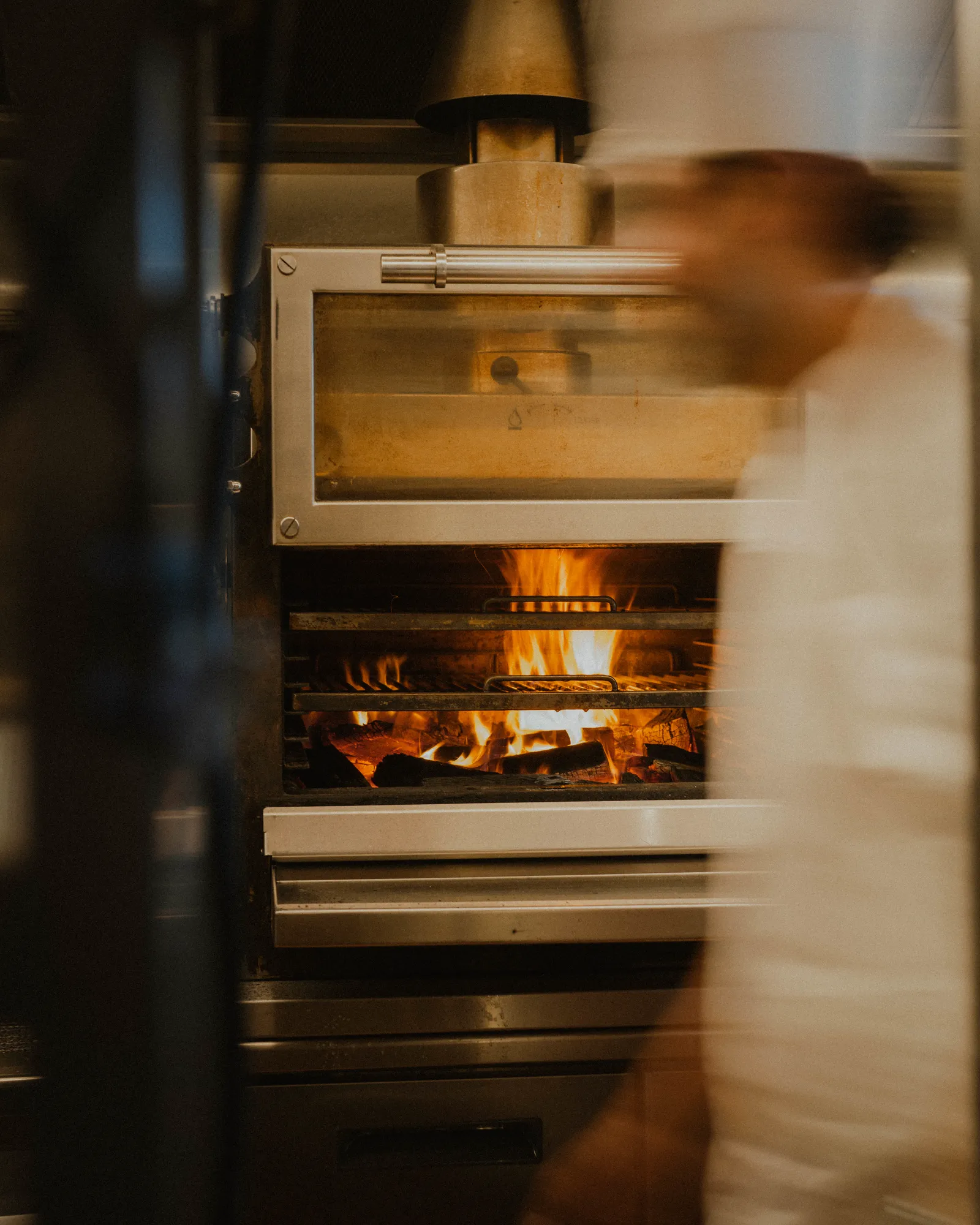 A chef at the charcoal oven in the open kitchen at Faucher
