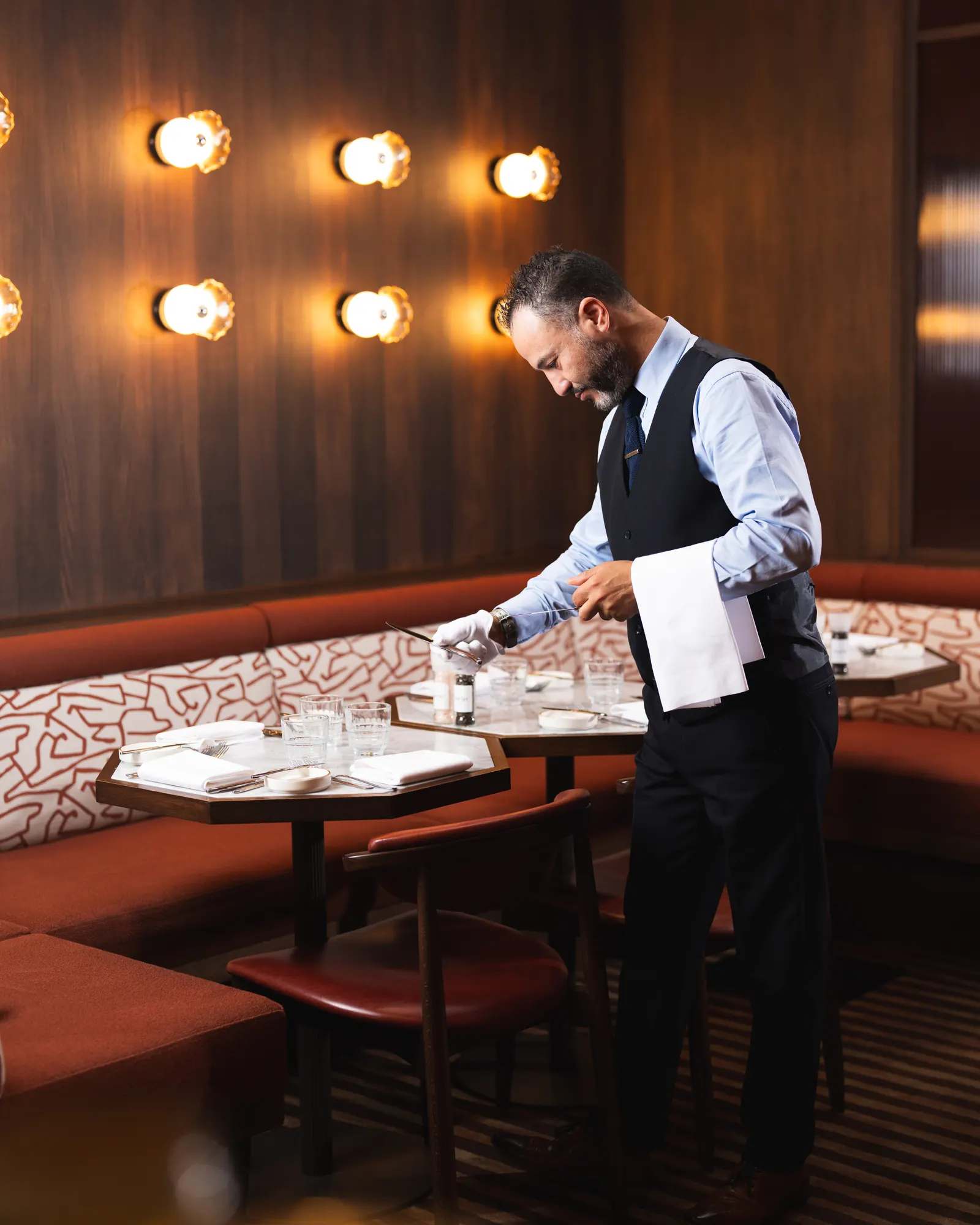 Een zaalmedewerker van Faucher dekt een tafel